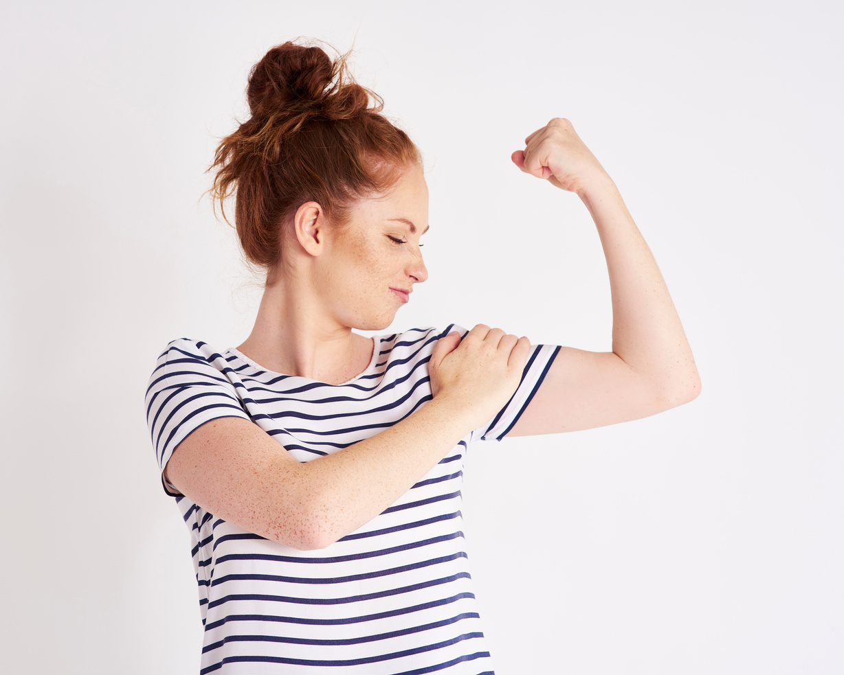 Confident and strong woman showing her bicep at studio shot